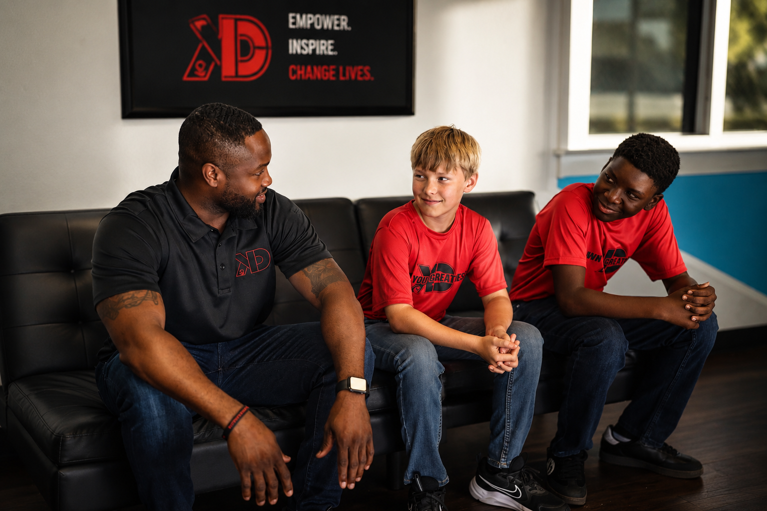 A mentor sitting with two young men at a school site, talking and building trust.